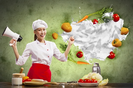 Asian female cook holding megaphone vegetables flying in airの写真素材