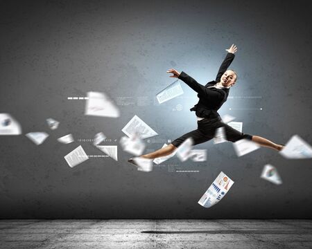 Image of pretty businesswoman jumping high against financial backgroundの写真素材