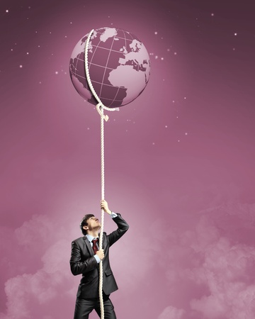 Image of businessman climbing rope attached to earth planetの写真素材