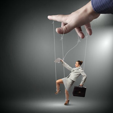 Businesswoman marionette on ropes with suitcase in handの写真素材