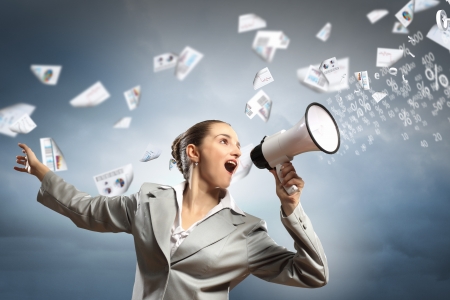 businesswoman in grey suit screaming into megaphoneの写真素材