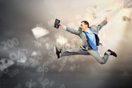 Image of a businessman jumping high against financial backgroundの写真素材