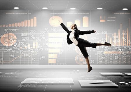 Image of pretty businesswoman jumping high against financial backgroundの写真素材