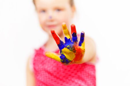 little child with hands painted in colorful paints ready for hand printsの写真素材
