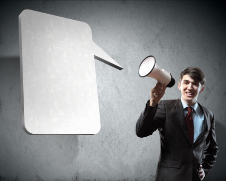 young businessman smiling in black suit holding megaphoneの写真素材
