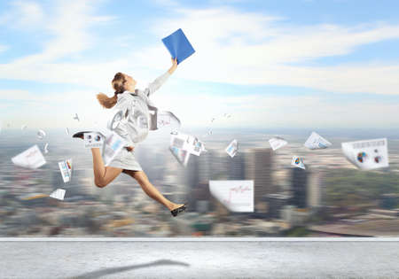 Image of a businesswoman jumping high against financial backgroundの写真素材