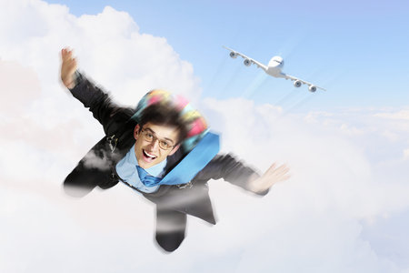 Conceptual image of young businessman flying with parachute on backの写真素材