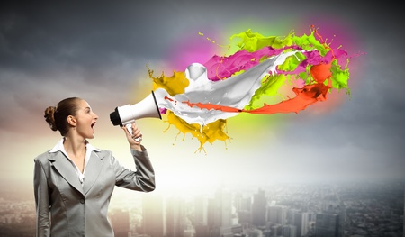 businesswoman in grey suit screaming into megaphoneの写真素材