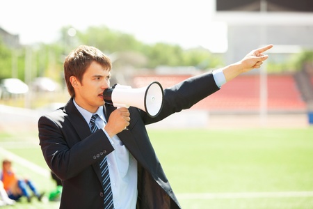 Businessman in black suit with loudspeaker at athletic stadiumの写真素材