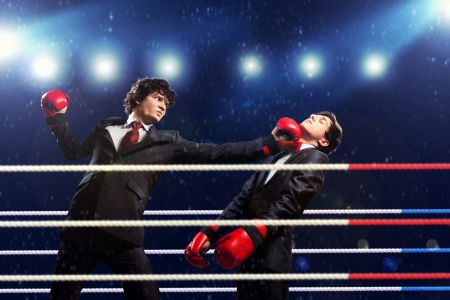 Two young businessman boxing againts dark background   conceptual collageの写真素材
