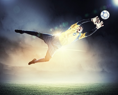 Goalkeeper catches the ball   At the stadium, in the spotlight の写真素材