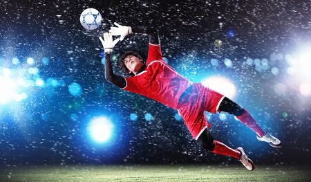 Goalkeeper catches the ball   At the stadium, in the spotlight の写真素材