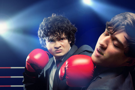 Two young businessman boxing againts dark background   conceptual collageの写真素材