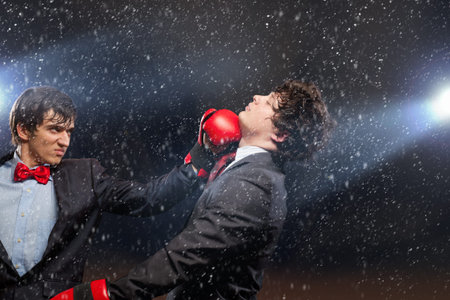 Two young businessman boxing againts dark background   conceptual collageの写真素材
