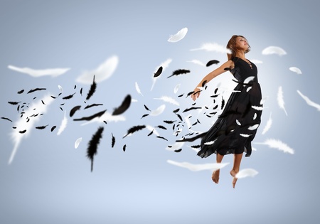 Young girl flying among the feathers like a birdの写真素材