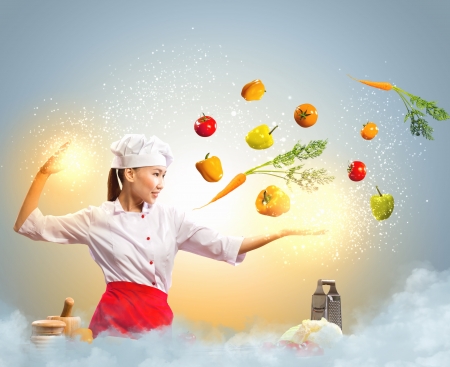 Asian female cooking with magic against color backgroundの写真素材