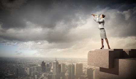 Image of businesswoman looking in telescope standing a top of buildingの写真素材