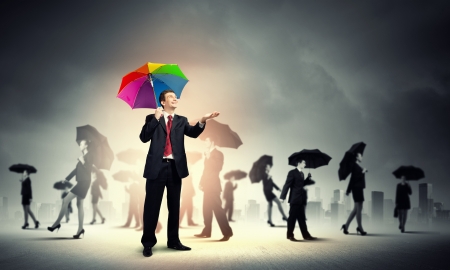 Image of pretty businessman with umbrella walking in crowd of peopleの写真素材