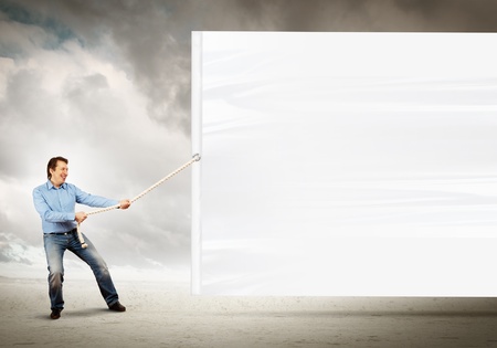 Adult man pulling blank banner  Place for textの写真素材