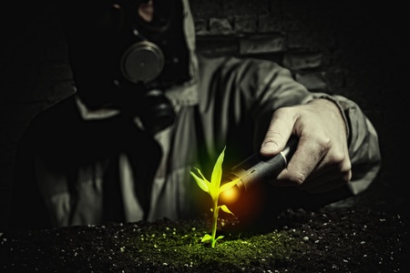 Young man in a protective suit touches to the sprout  post-nuclear futureの写真素材