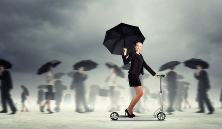 Image of young businesswoman in black riding scooter