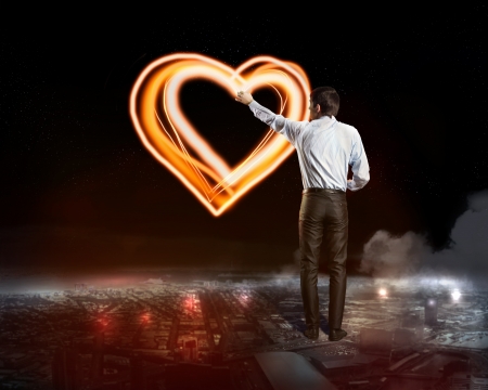 Businessman draws a glowing signs in the dark skyの写真素材