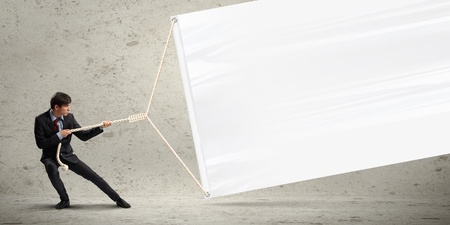 Image of young businessman pulling blank banner  Place for textの写真素材