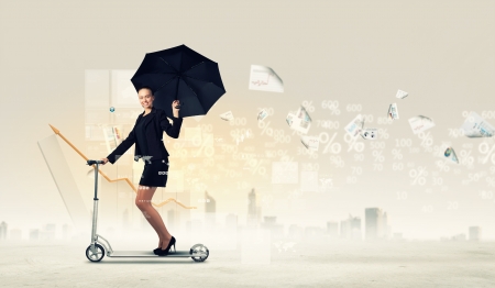 Image of young businesswoman in black riding scooterの写真素材