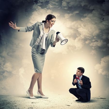 Angry businesswoman with megaphone shouting at colleagueの写真素材