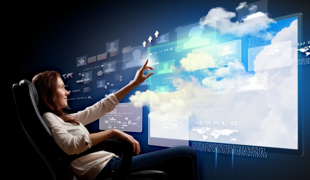 Young woman in armchair pushing icon on media screenの写真素材