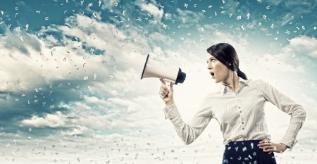 Image of young businesswoman screaming in megaphoneの写真素材