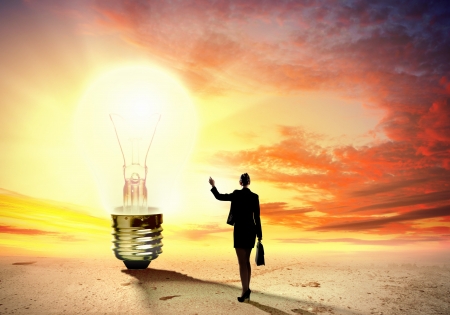 Image of businesswoman looking at light bulb  Green energy conceptの写真素材