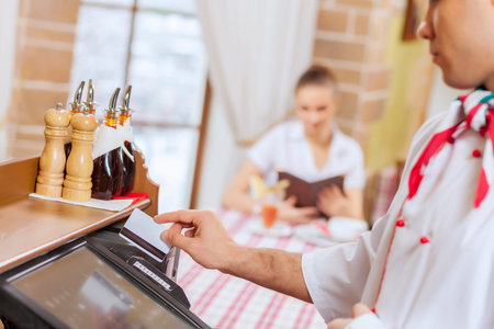 Image of handsome chef inserting card in terminal