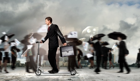 Image of young businessman in black suit riding scooterの写真素材