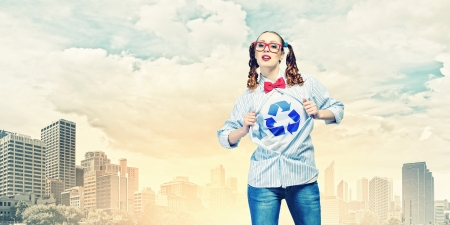 Young woman acting like super hero with recycle sign on chestの写真素材