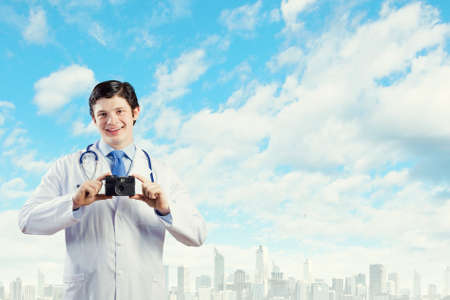 Young funny doctor taking photos with phone cameraの写真素材
