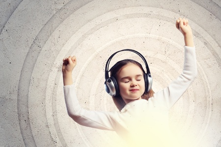 Little girl in headphones with eyes closed enjoying musicの写真素材