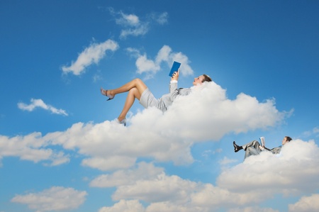 Image of businesspeople lying on clouds with tablet pcの写真素材