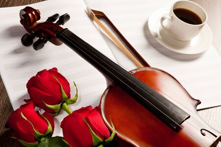 Red roses and a violin on the tableの写真素材