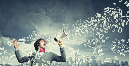 Portrait of young man shouting loudly using megaphoneの写真素材