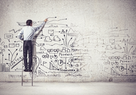 Back view of businessman drawing sketch on wallの写真素材