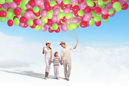 Happy young family walking holding bunch of colorful balloonsの写真素材