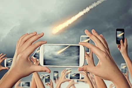 Close up of human hands taking photo of falling meteoriteの写真素材