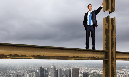 Business man standing high over a cityscapeの写真素材