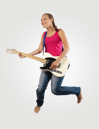 young woman playing on electro guitar and jumpingの写真素材