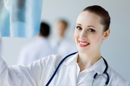 Attractive female doctor in white uniform with colleagues at backgroundの写真素材