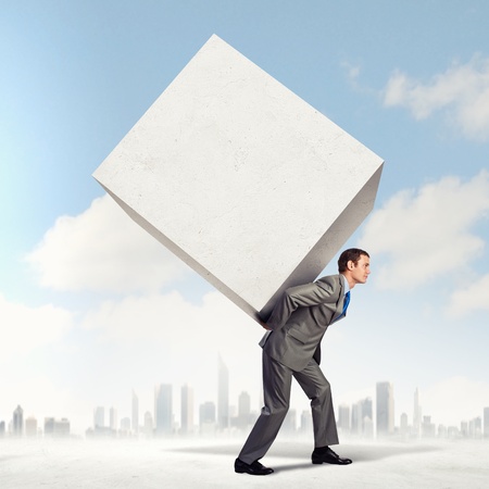 Image of businessman carrying big white cube on his backの写真素材