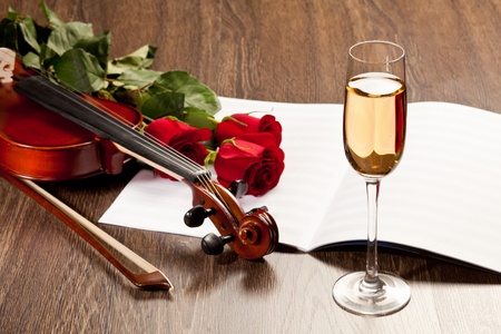 Red roses and a violin on the tableの写真素材