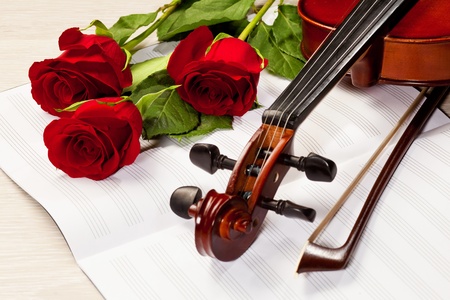 Red roses and a violin on the tableの写真素材