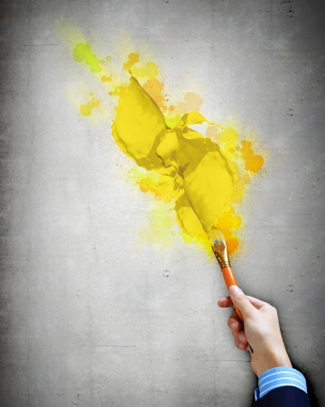 Close-up of human hand holding paint brush making colorful paint splashesの写真素材